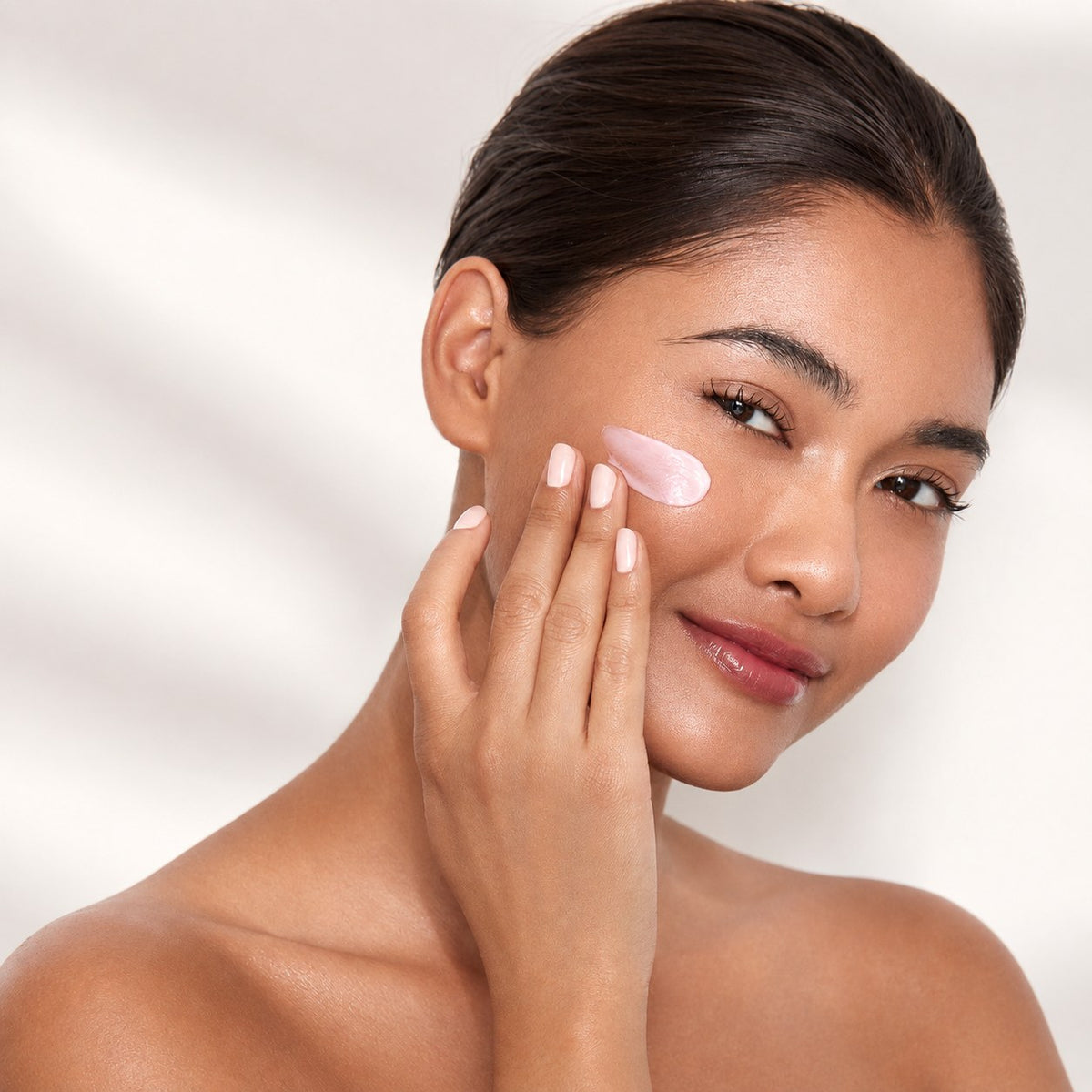 Woman applying pink suyé cream to her cheek