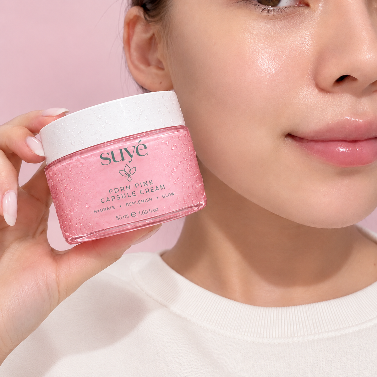 Woman with glowing skin holding a jar of Suye Skin PDRN Collagen Jelly Cream next to her face